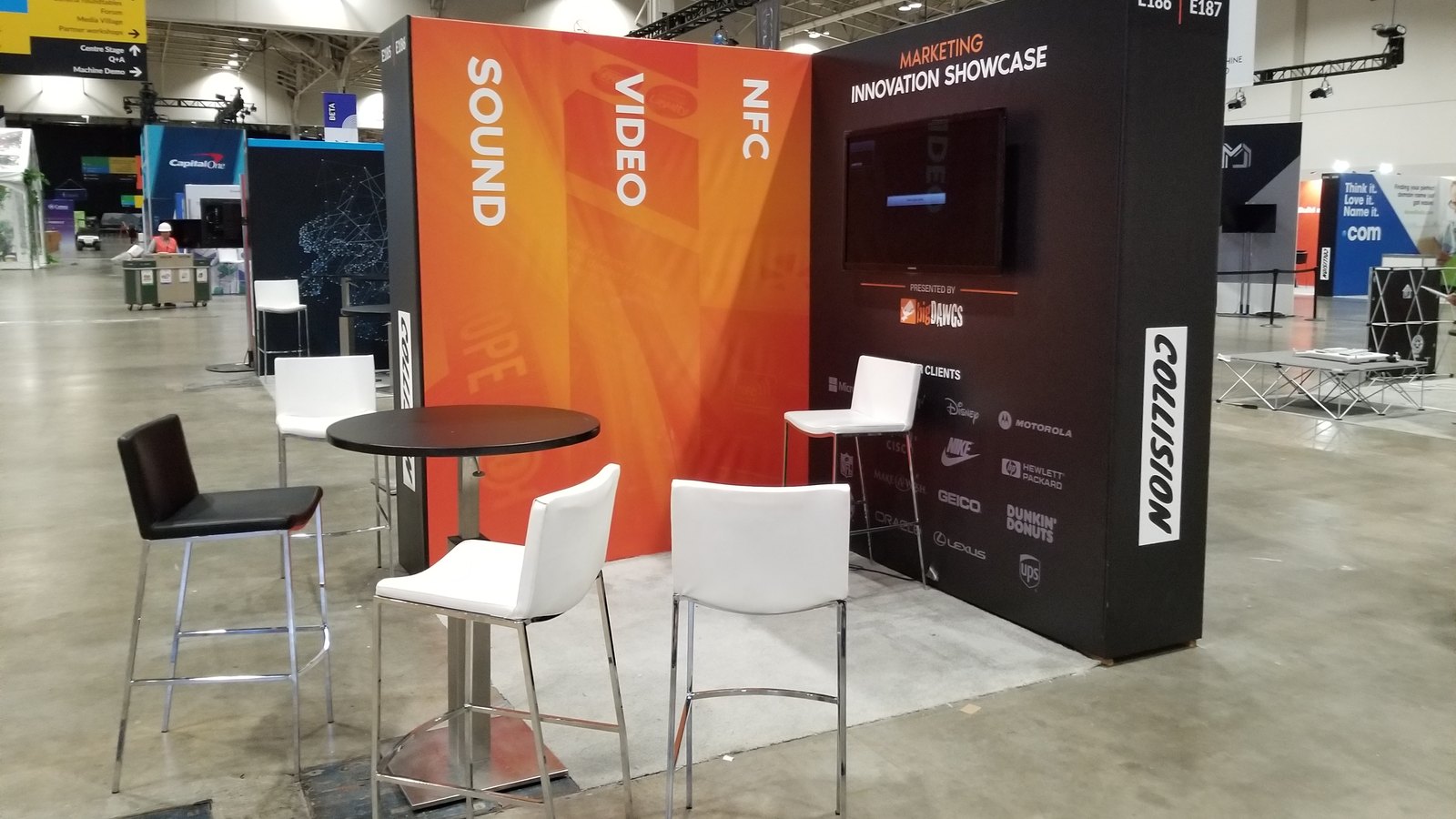 The bigDAWGS booth at Collision Toronto 2019: an orange wall reading Sound, Video, NFC and a black Marketing Innovation Showcase wall with a screen and client logos