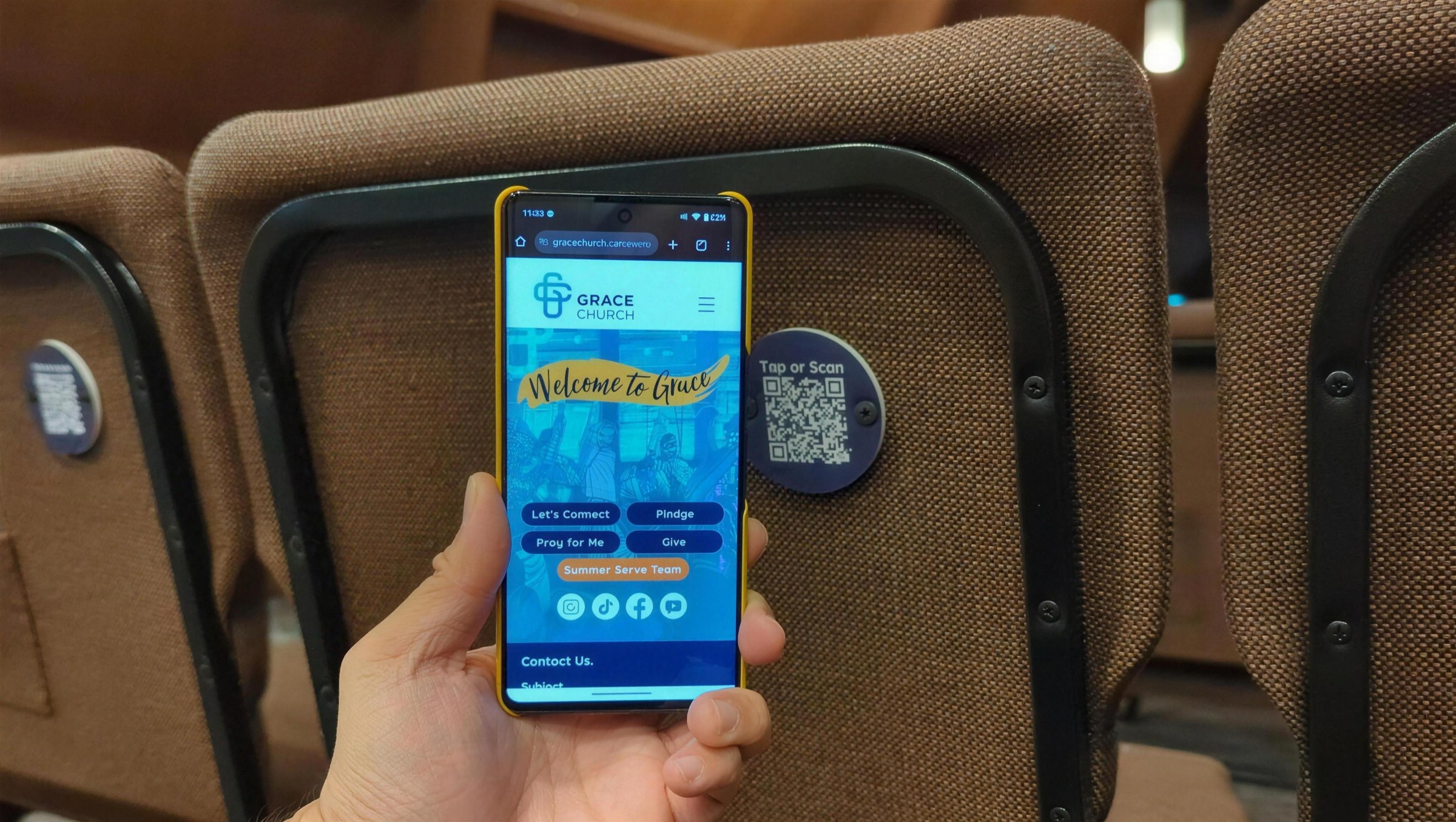 A phone showing the Grace Church page next to a plaque on a chair