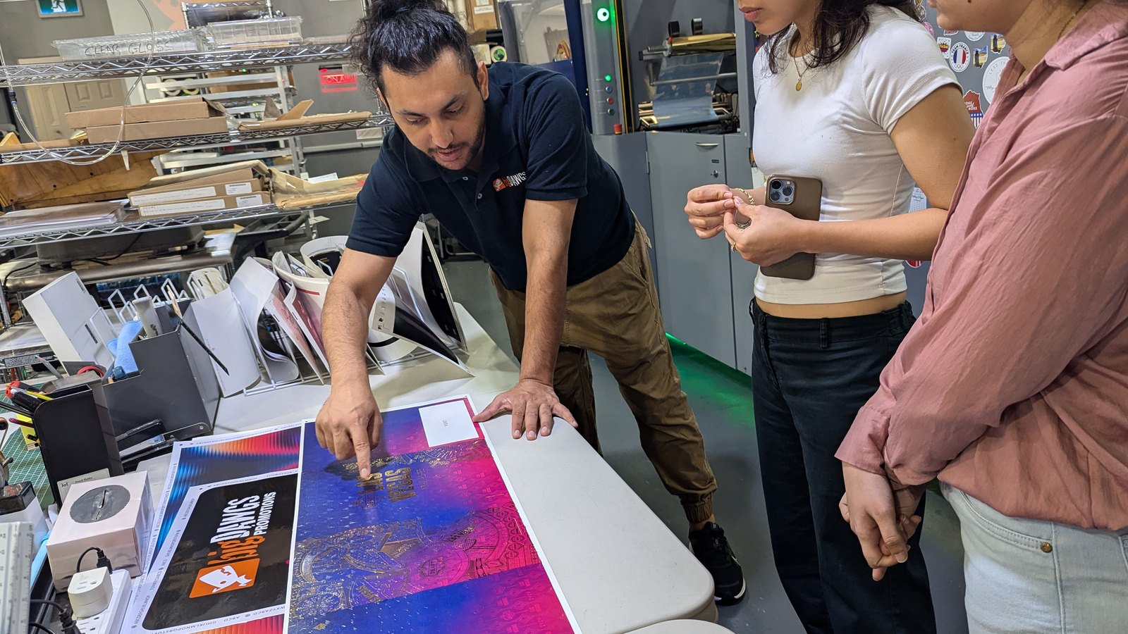 Karan pointing out detail on a printed press sheet to two interns