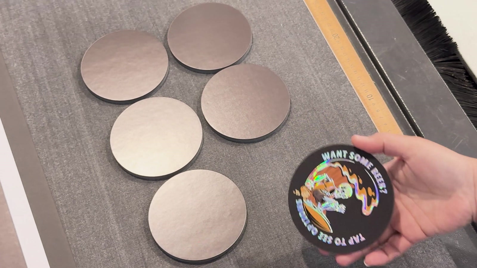 Video frame: a holographic coaster with an NFC chip, next to blank coasters