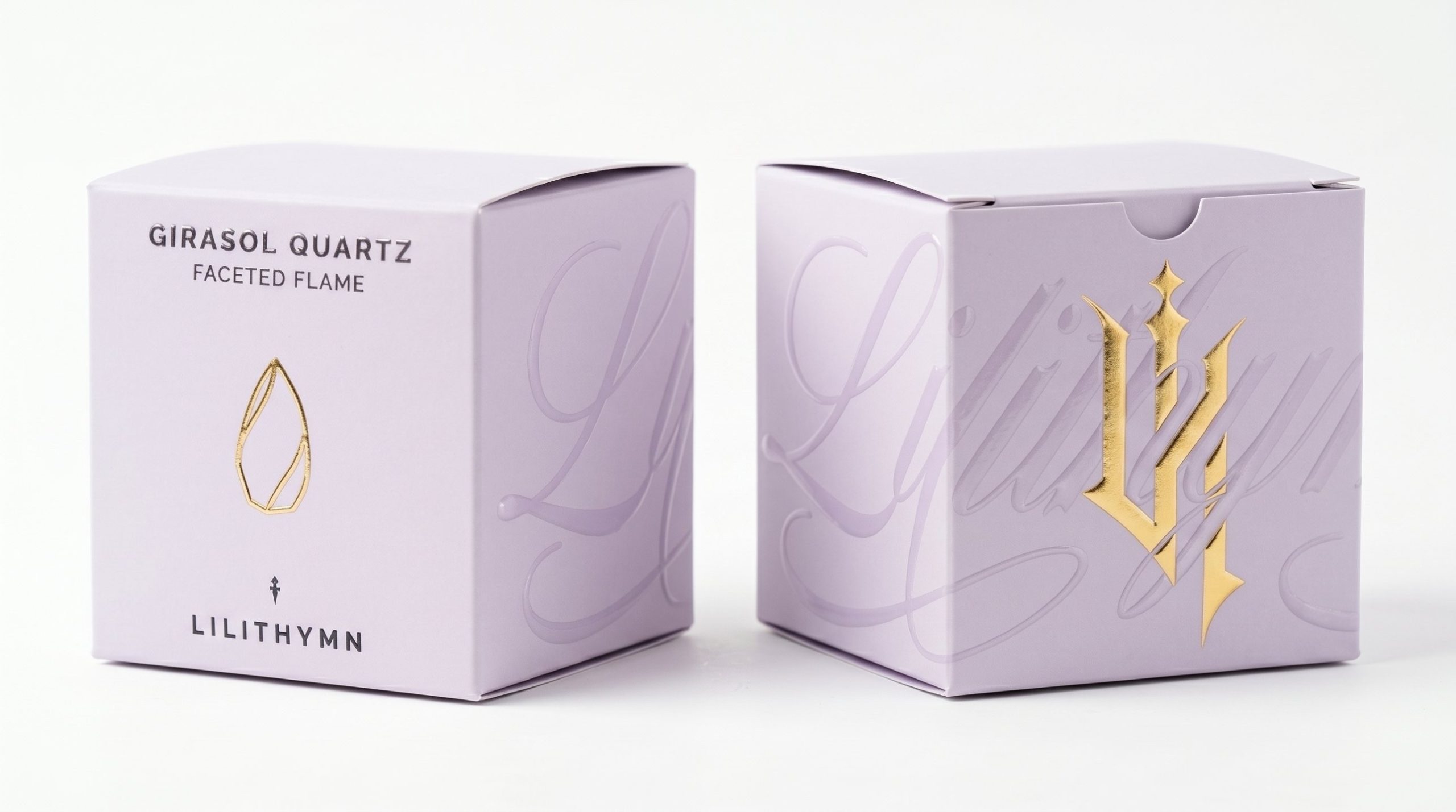 Render of two lavender crystal boxes, one with the product name and a gold foil flame, one with a gold foil monogram over a raised varnish script