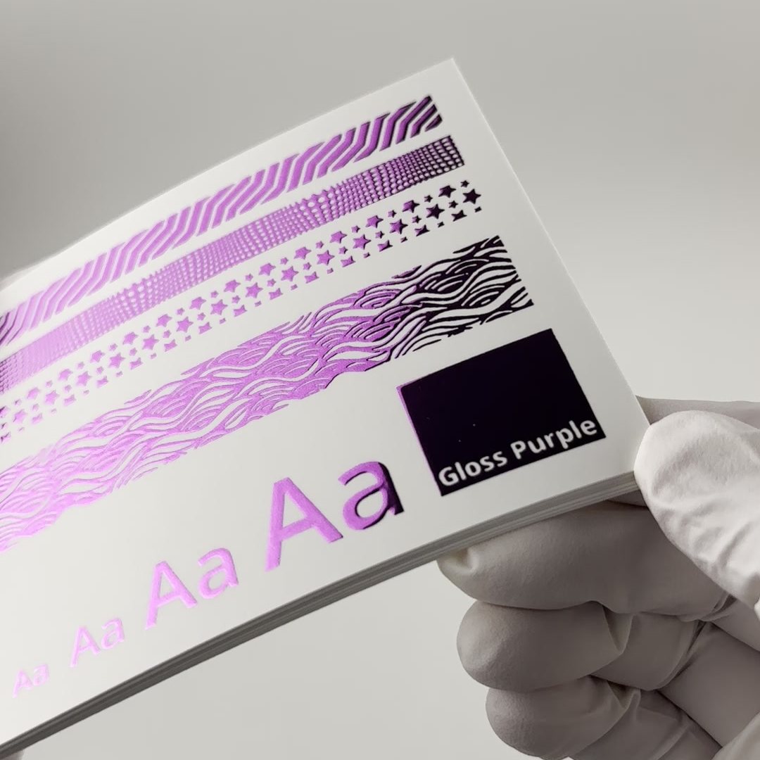 Foil swatch card in gloss purple foil, held in a gloved hand