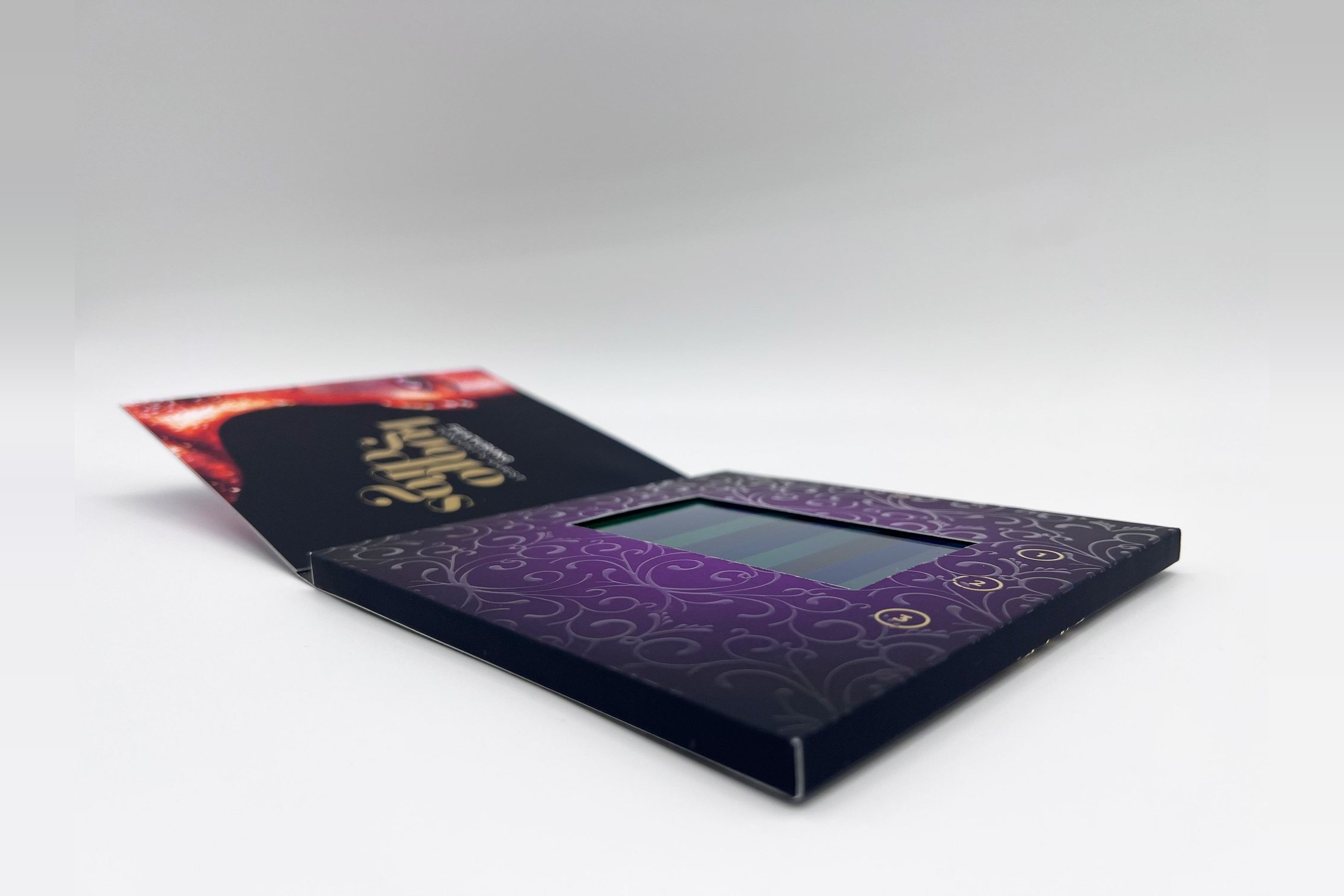 Printed video card lying open, its screen set into a printed cover that wraps the whole module