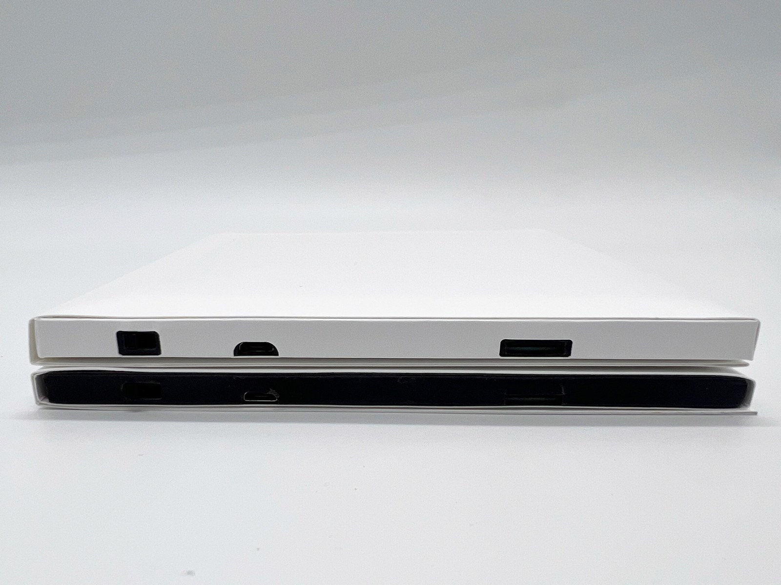 A white full wrap video card stacked on a standard video card: the full wrap is white along its edge and ports, the standard card shows a black band