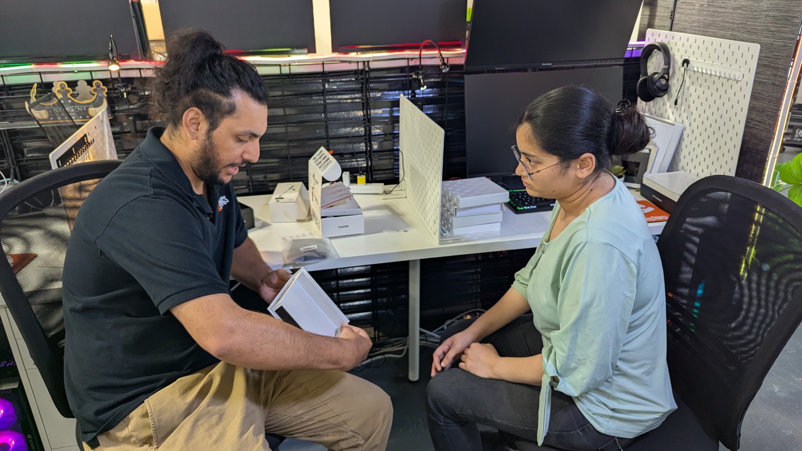 Karan reviewing a white prototype box with Sana at her desk