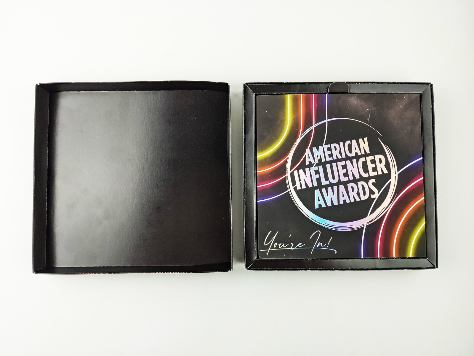 The box open: the empty lid beside the tray, with the American Influencer Awards video card sitting on top